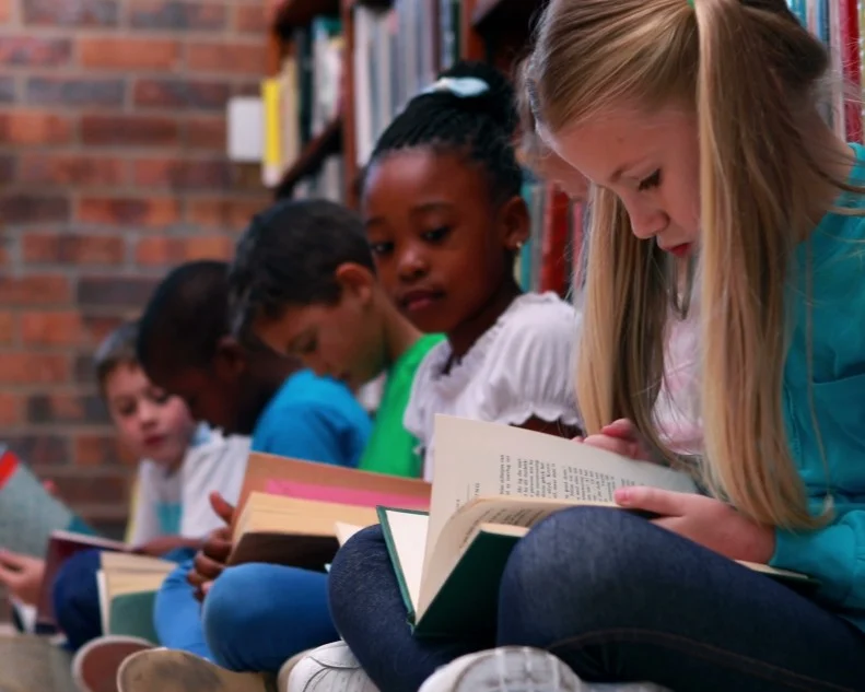 A diverse group of students reading books together in a school library