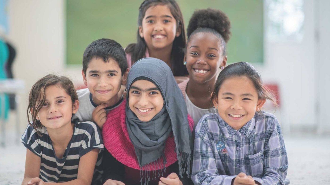 Six smiling children gathered together in a classroom